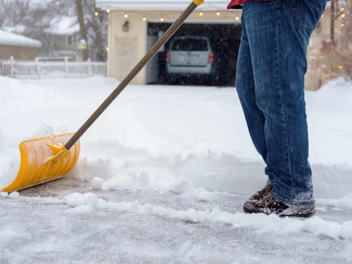Man shoveling driveway during winter snowstorm